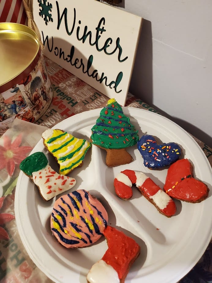 Best Gingerbread Cookie Recipe. gingerbread cookies on a plate with a sign that says winter wonderland in the background. the cookies are all colors with icing all over the top.