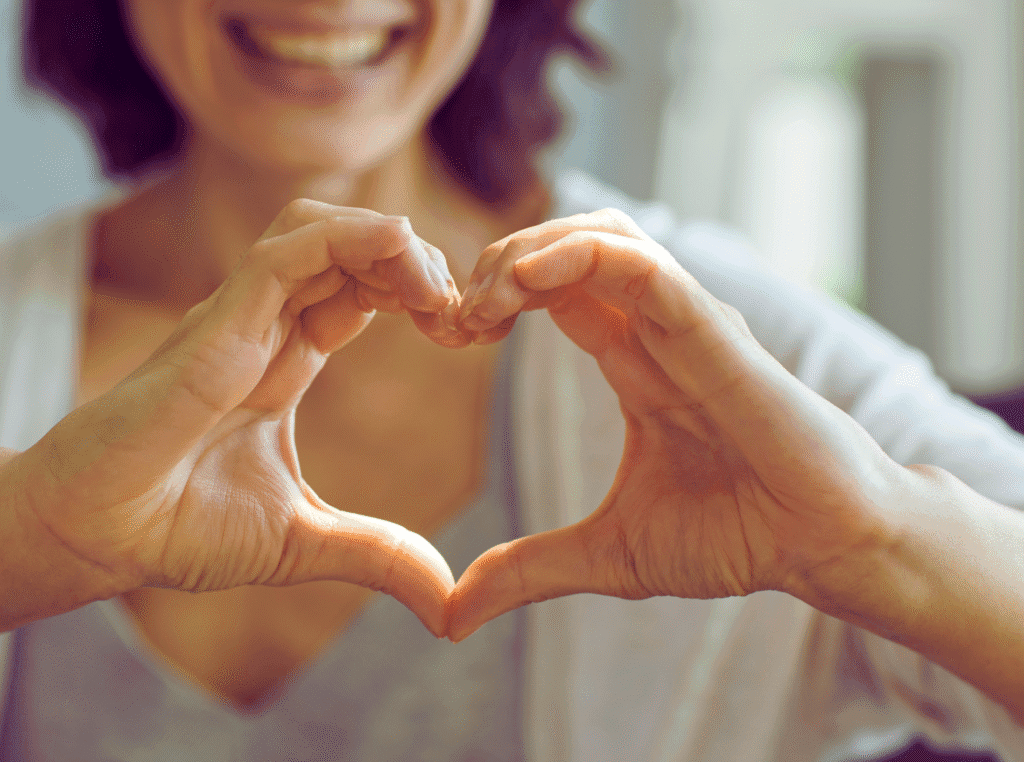 How to find your purpose in life. woman smiling with her hands in the shape of a heart in front of her.