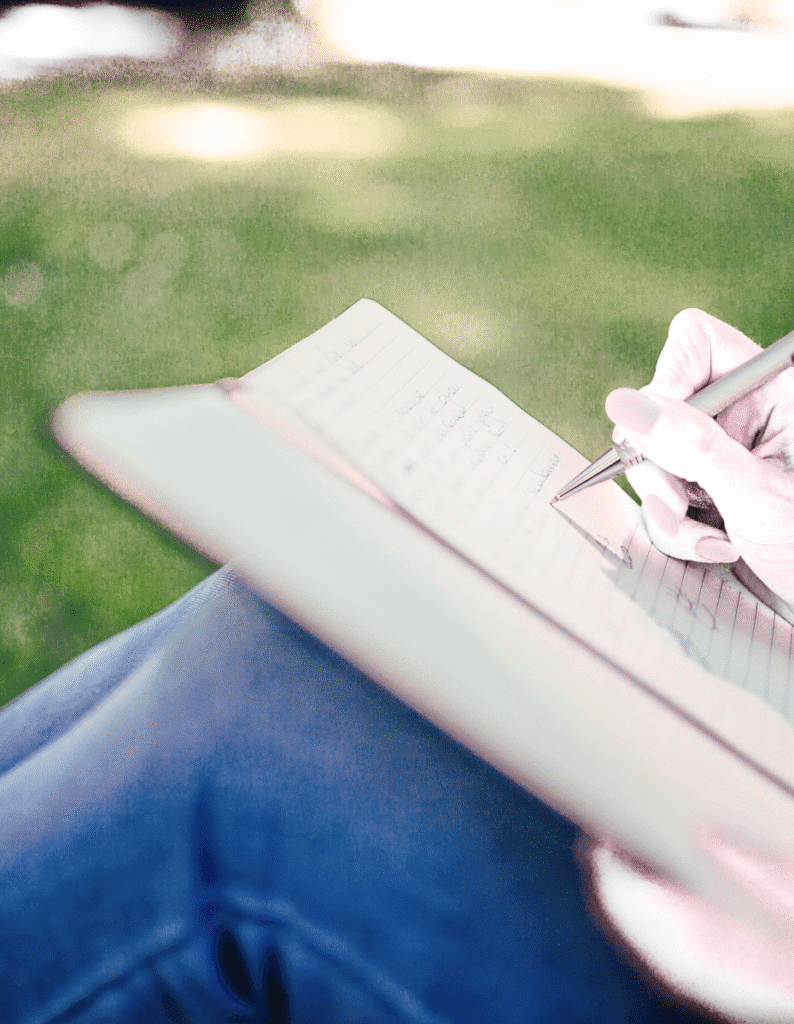 How to Change Your Mindset. woman sitting in the grass journaling with a pen and notebook.