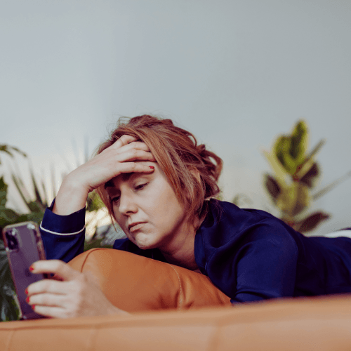 How to Make Money Online for Beginners. woman laying on her bed looking at her phone looking frustrated