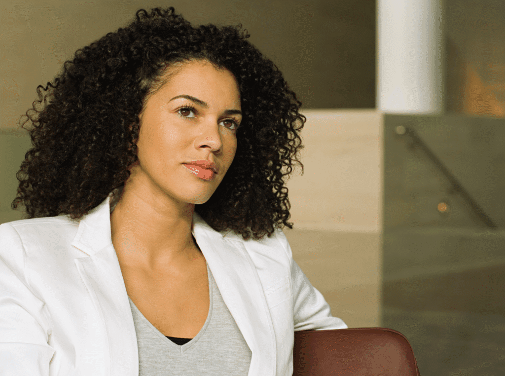 How Do You Find Your Niche Market? african american woman with a white blouse sitting looking in the distance thinking.