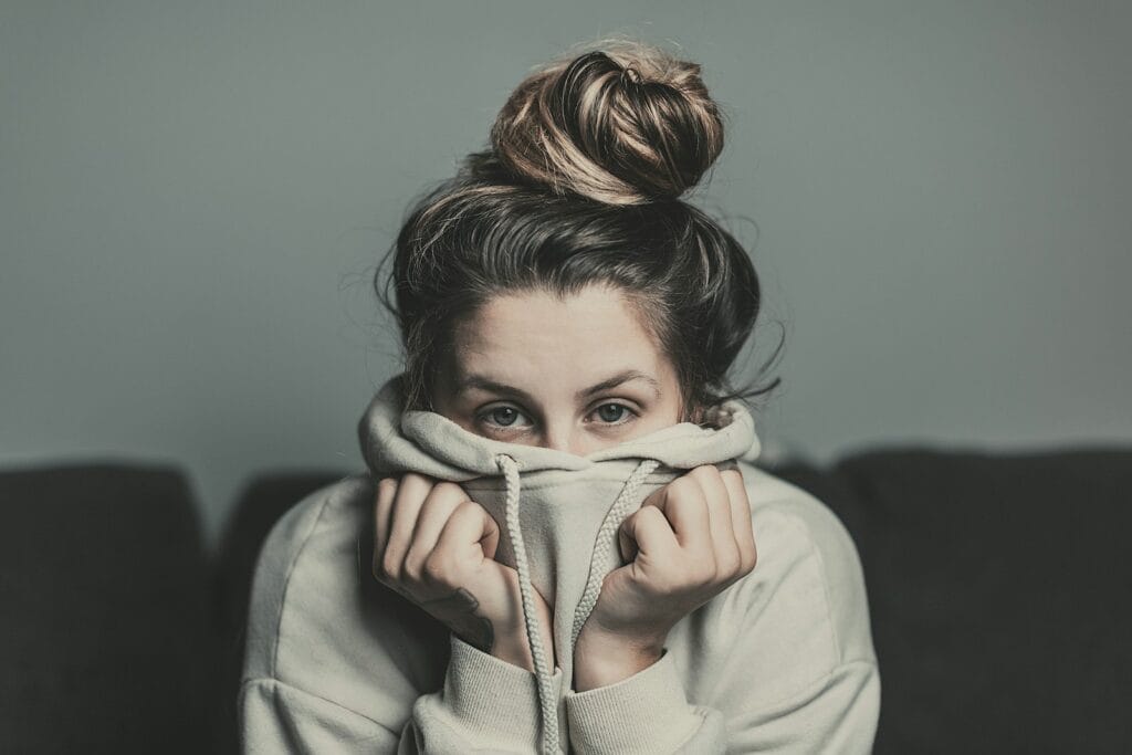 be the person you want to be. woman in white hoodie covering her face with her hands