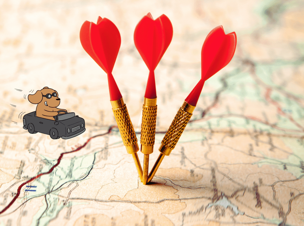 affiliate marketing on pinterest without a blog. image of a map laying flat with 3 red darts stuck into it at about the same location. and an image of a puppy dog driving a ittle car toward it with his ears back like the wind is blowing them back. to represent plain english roadmap.