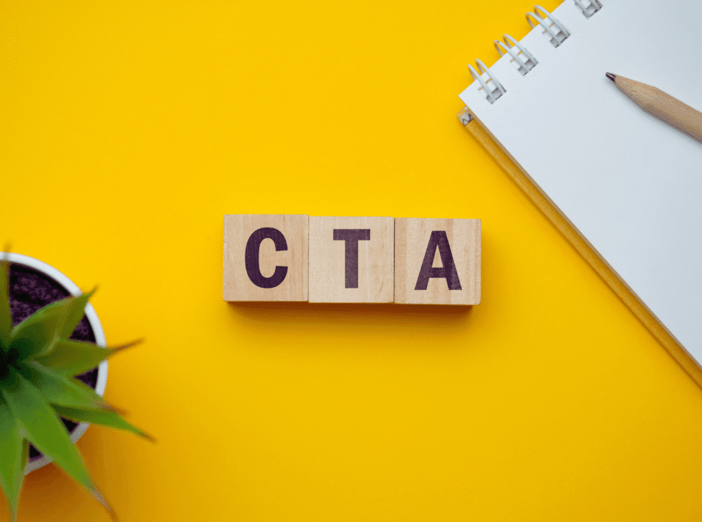 Call to action examples. yellow background with a pad and pencel off to the right side and in the center of the photo, are the letters CTA in wooden blocks. 