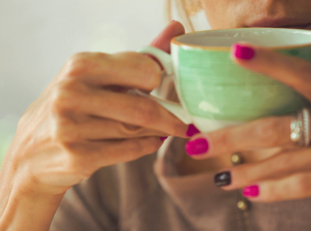 How do you know when God is talking? woman with cup of tea sipping, different color nail polish on her nails.