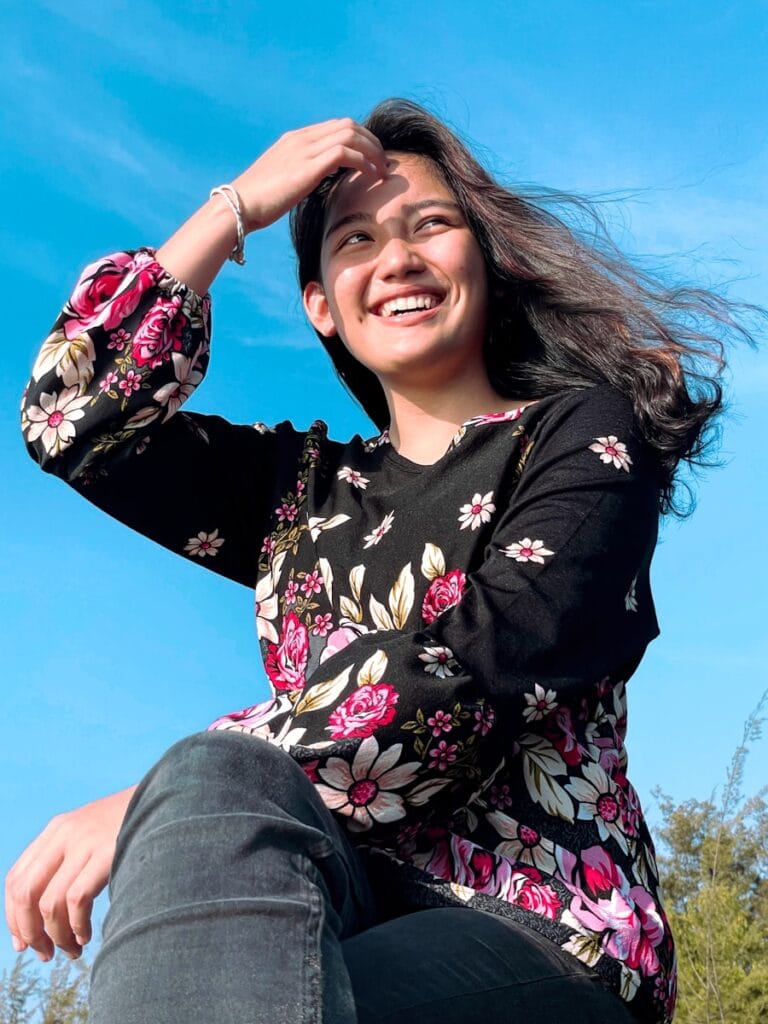 be the person you want to be. a woman sitting on the ground with her hair blowing in the wind