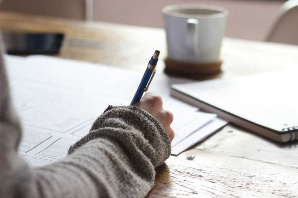 What should I write about? person writing on brown wooden table near white ceramic mug