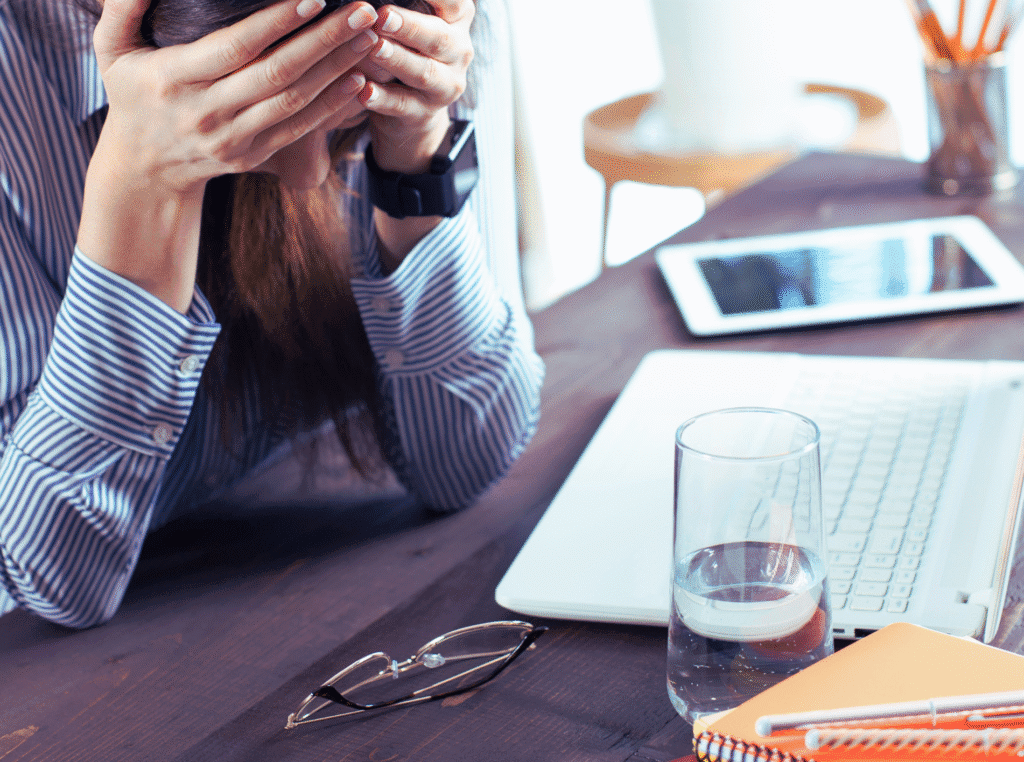 What should I write about? woman with her head in her hands in front of her laptop because she doesn't know what to write.