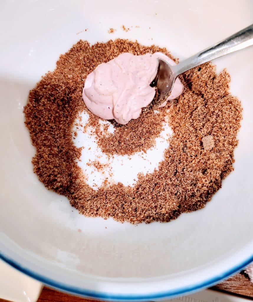 Health benefits of flax seed oil. bowl of ground flax seeds with the beginnings of cottage cheese mixture with fruit. making the budwig museli.