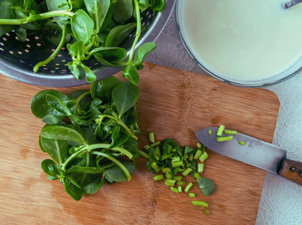 What is purslane used for. bowl with purslane and blackberries in it. a cutting board next to it with a knife and more purslane being chopped next to it.