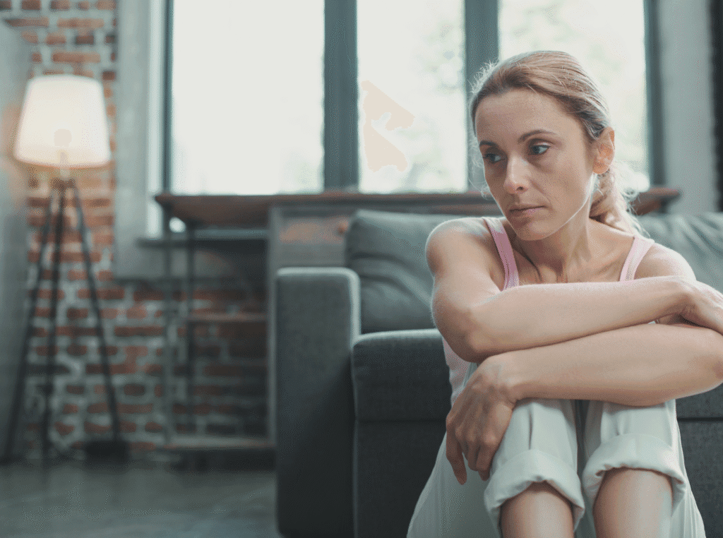 be a good person. sad woman sitting on the floor with her knees to her chest and her arms on her knees. 