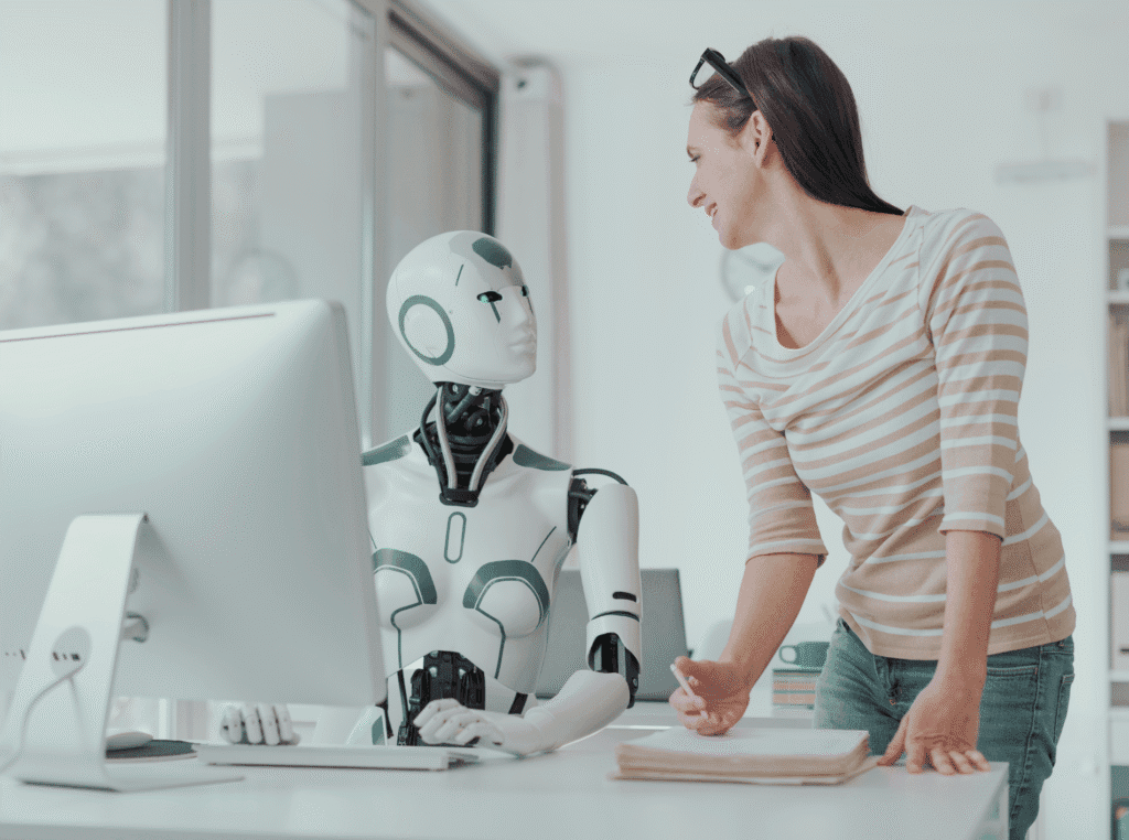 people who pretend to care. woman standing next to an ai robot sitting in front of a computer like the ai robot is doing the work.