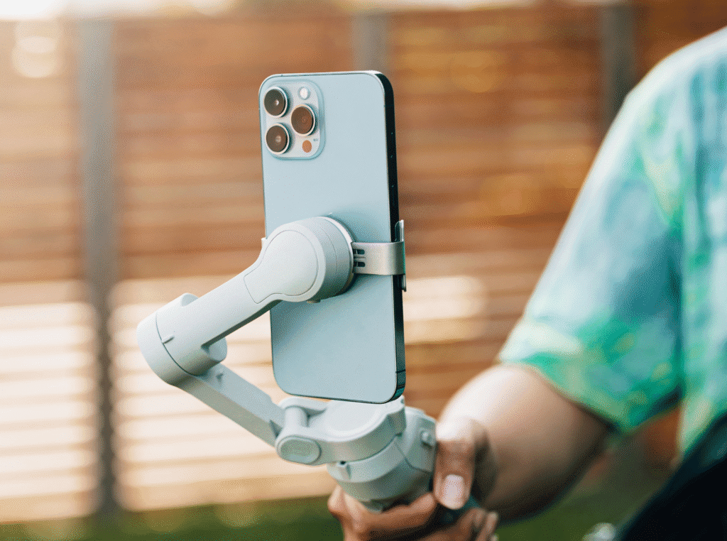 phone gimbal stabilizer. person holding a gimbal stabilizer with their phone attached to it like they're recording a video. 