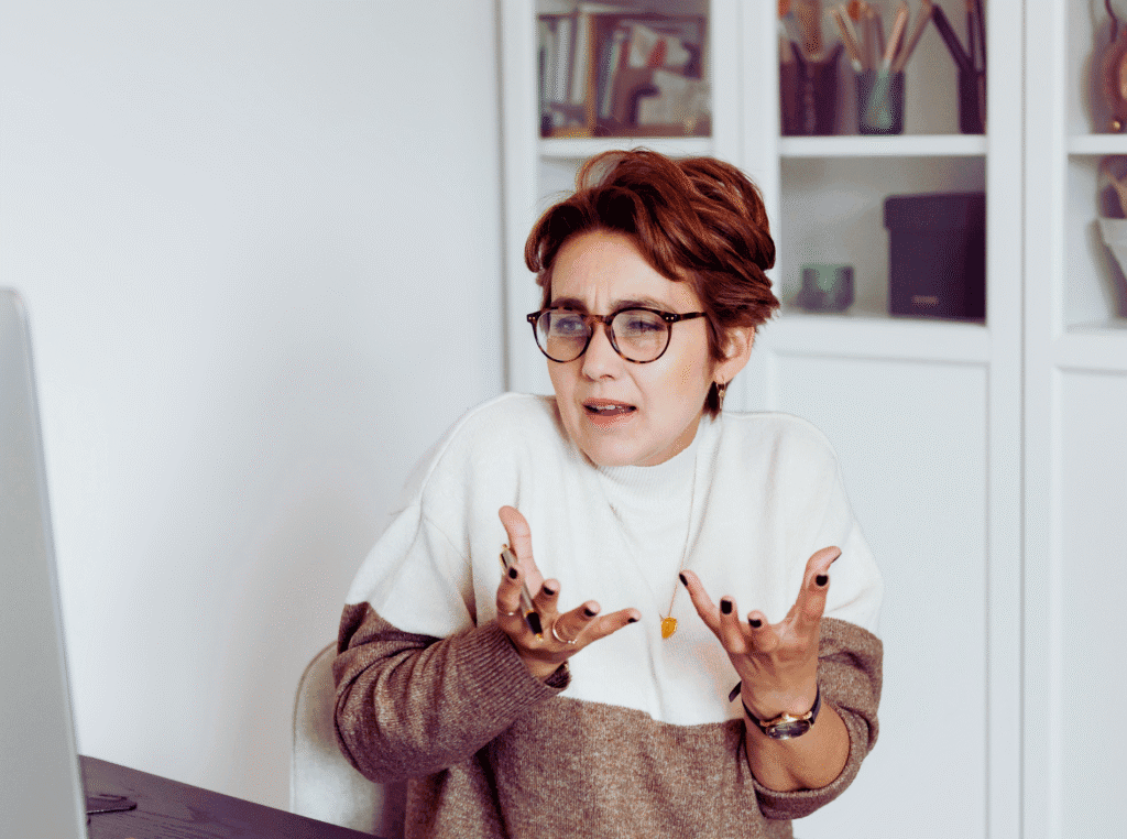 What does a digital marketer do. woman in front of her computer with a confused look on her face. hands in front of her like what do I do. she has glasses on.