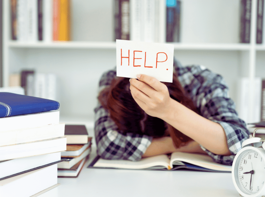 christians get discouraged. woman with her head on a desk and she's holding up a piece of paper that says: Help.