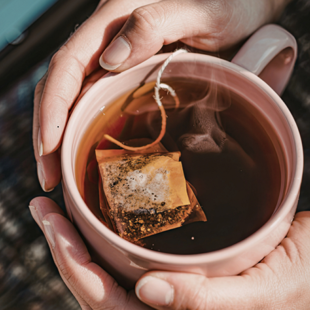 holding a cup of tea with a teabag in it