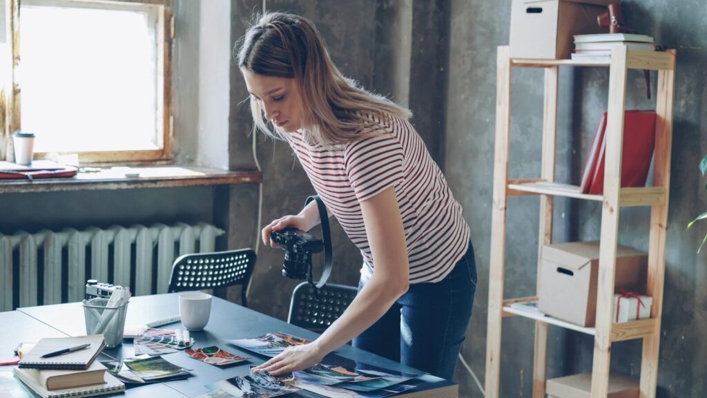faceless video ideas. Woman arranging photos on a desk while holding a camera