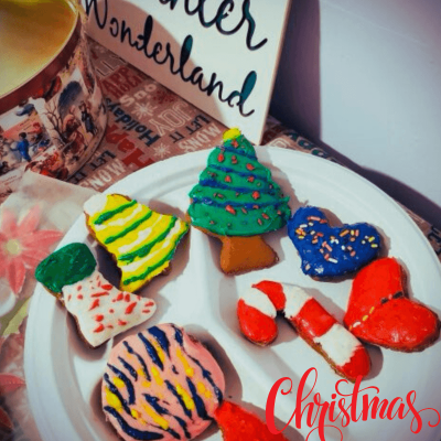 Best Gingerbread Cookie Recipe. gingerbread cookies on a plate with a sign that says winter wonderland in the background. the cookies are all colors with icing all over the top.