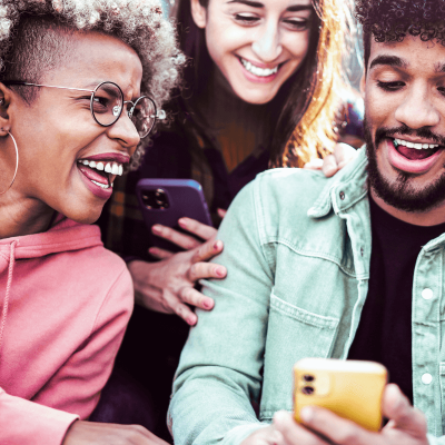 Does Social Media Affect Mental Health? 3 people looking at their phones. different ages, different races all laughing.