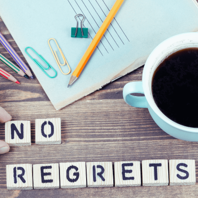 Live Life Without Regrets. paper and pencil with a cup of coffee next to it and the words no regrets spelled out in scrabble letters.
