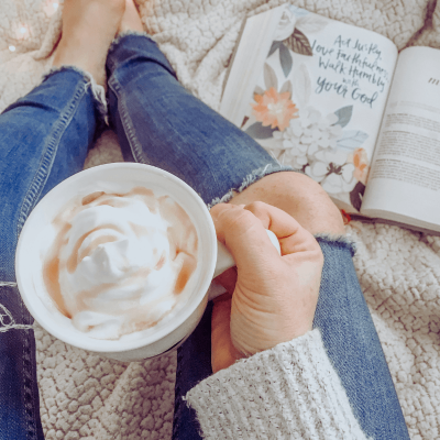 What to Do When You Lose Faith in God? Woman sitting with her coffe wearing sweater and torn jeans. Her Bible is open but on the floor next to her.