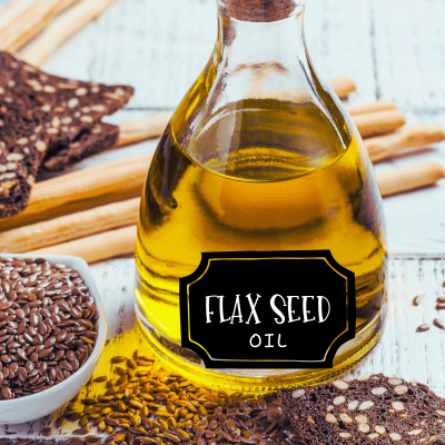 health benefits of flax seed oil. a clear bottle of flax seed oil with a label on the front that says flax seed oil. and whole flax seeds on the side of it.