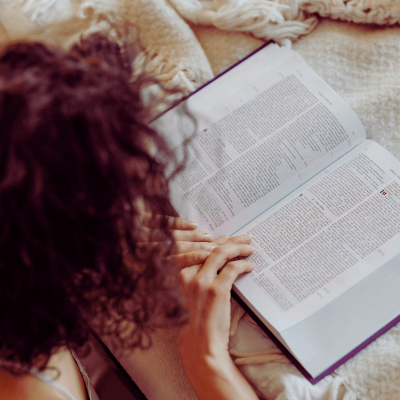 How do you know when God is talking to you? woman kneeling at bed reading her Bible.