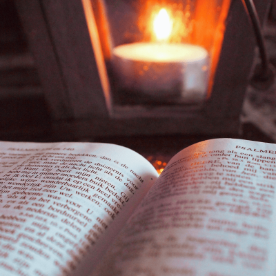 How to forgive and let go. image of an open bible and a lit candle in the background.
