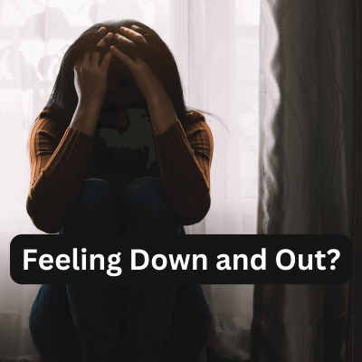 when you're down and out. woman sitting in front of a window with her head in her hands and her arms on her legs, she's on the floor and is distraught.